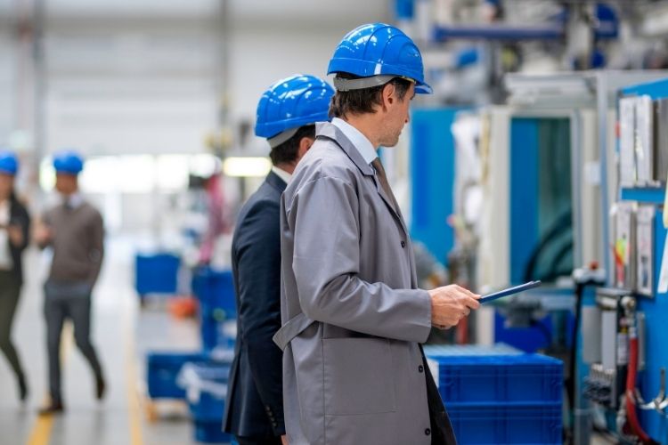 Two professionals discussing production beside factory equipment